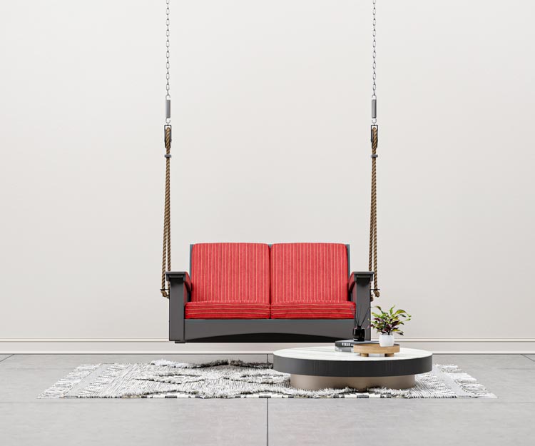 Hanging outdoor swing with red cushions over a rug.